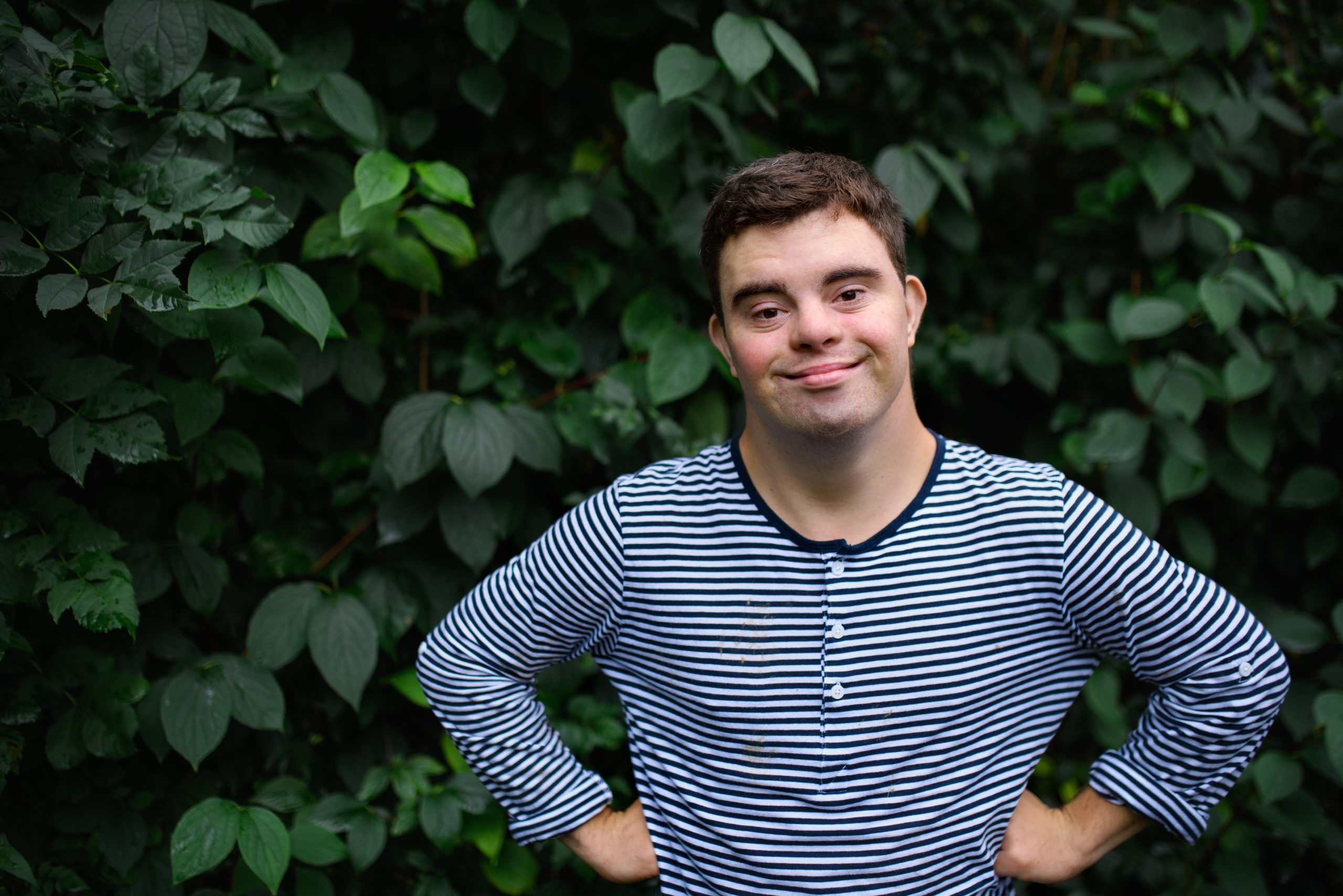 Portrait Of Down Syndrome Adult Man Standing Outdoors At Green 